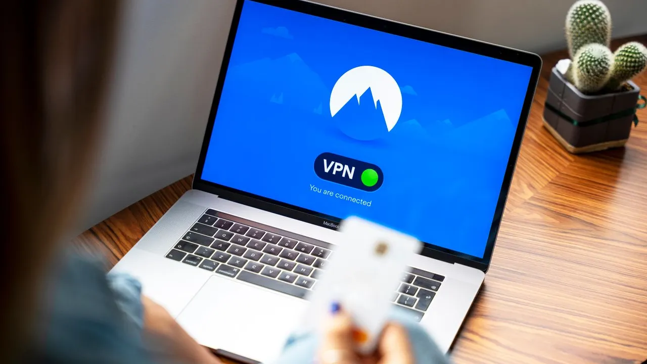 Seseorang memegang kartu di depan laptop dengan koneksi VPN aktif